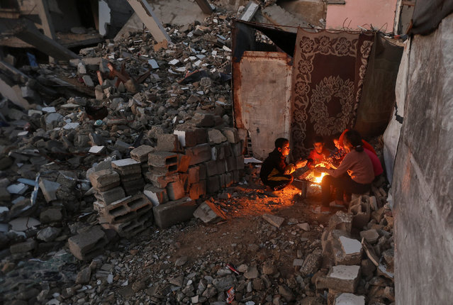 Palestinian children warm their hands over the fire on a rainy day in Khan Younis, southern Gaza Strip, on November 25, 2025. (Photo by Ramadan Abed/Reuters)