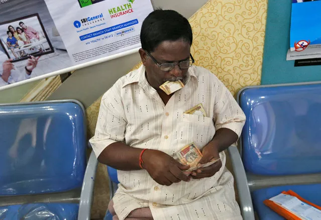 A man counts 500 and 1000 Indian rupee banknotes before depositing them in a bank in Mumbai, India, November 10, 2016. (Photo by Danish Siddiqui/Reuters)