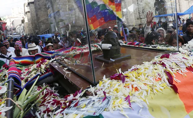 Crowds accompany the Bolivian deity statuette “illa of Ekeko” as it is driven to the Alasitas Fair, in which Ekeko is the central figure, in La Paz, Bolivia, Saturday, January 24, 2015. (Photo by Juan Karita/AP Photo)