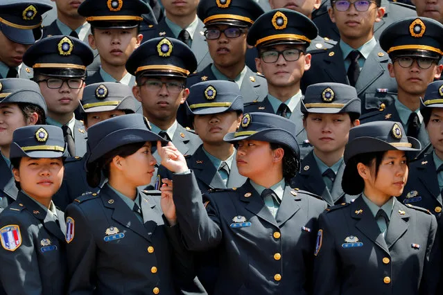 A graduate adjusts the hat of a fellow graduate while preparing for a group photo after the joint military academies graduation ceremony, in Taipei, Taiwan June 29, 2018. (Photo by Tyrone Siu/Reuters)