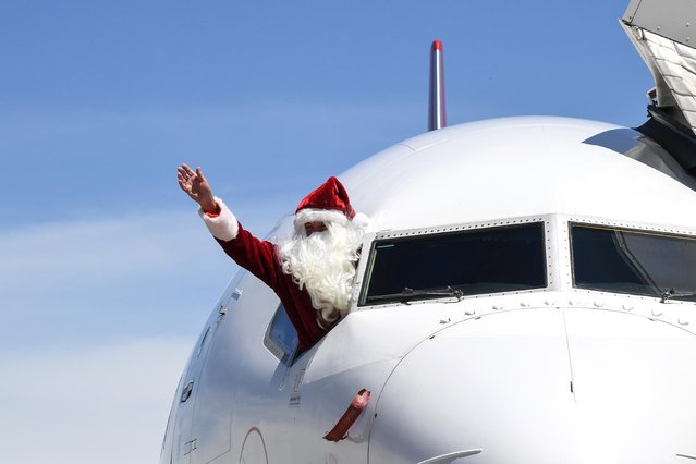 Qantas Captain Steve Anderson dressed as Santa Claus waves from the cockpit of his Boeing 737 aircraft at Brisbane Airport before departing to Mackay on December 16, 2020 in Brisbane, Australia. Captain Anderson has been flying for Qantas for 41 years and has spent more than half of those years flying as Santa Claus during the festive season. The Australian airline has increased domestic flights to around 70% of pre Covid-19 capacity in time for reunions between families and loved ones. Santa Claus will be in command of a number of flights across the next week around Australia including Christmas Day. (Photo by James D. Morgan/Getty Images)