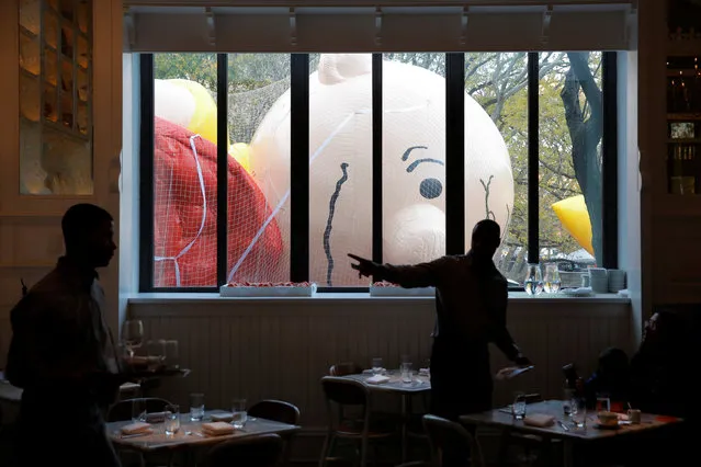 Wait staff work in the Storico restaurant beside the inflated Charlie Brown balloon ahead of the 90th Macy's Thanksgiving Day Parade in Manhattan, New York, U.S., November 23, 2016. (Photo by Andrew Kelly/Reuters)