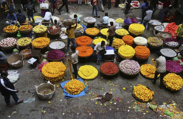 Indian vendors selling floral garlands wait for customers at a wholesale market in Bangalore, India, Thursday, August 9, 2018. Floral garlands in India are generally used for weddings and religious rituals, among others. (Photo by Aijaz Rahi/AP Photo)