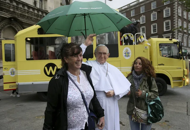 Tourists pose for photos with a newly unveiled wax work of Pope Francis ahead of Pope Francis' visit to Ireland, in Dublin, Thursday August 23, 2018. (Photo by Brian Lawless/PA Wire via AP Photo)