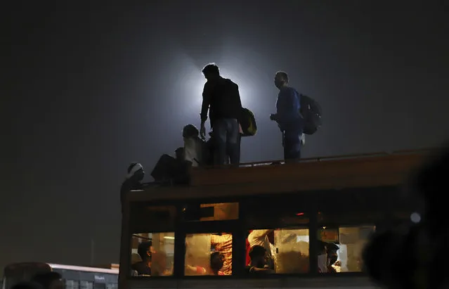 Migrant workers leave for their villages from a bus terminal, in New Delhi, India, Monday, April 19, 2021. (Photo by AP Photo/Stringer)