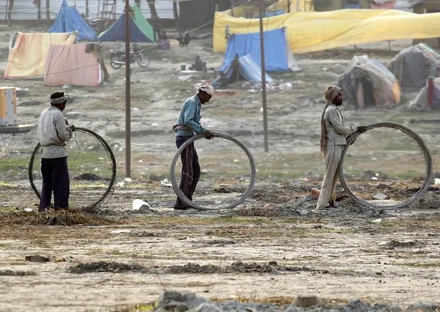 Labourers roll back electric wire, which was used to provide electricity during the month-long Hindu annual religious festival of Magh Mela, on the banks of the river Ganges in the northern Indian city of Allahabad, February 12, 2015. (Photo by Jitendra Prakash/Reuters)