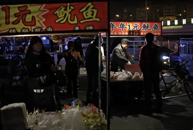 People buy foods from hawker stolls near a subway station in Beijing, Tuesday, January 19, 2016. China's slowdown is ratcheting up financial stress on companies while the country's leaders scramble to avoid a spike in job losses. Full-year 2015 growth of 6.9 percent was the lowest in 25 years, posing different challenges for investors, companies and the Chinese government. (Photo by Andy Wong/AP Photo)