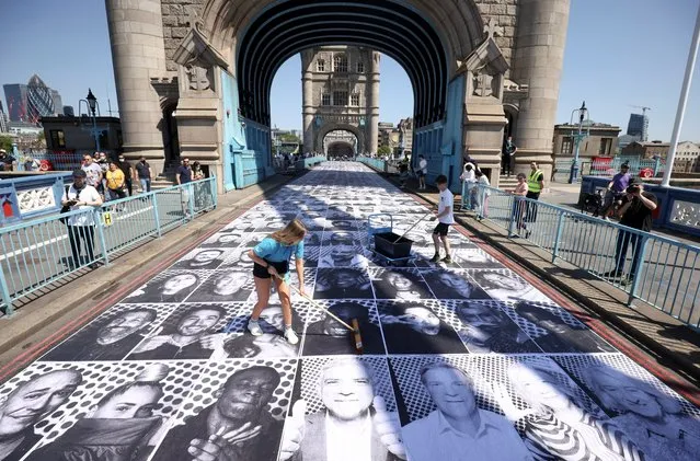 Workers place portraits of Londoners, including London's Mayor Sadiq Khan, by French artist JR, on the road at Tower Bridge to celebrate UEFA Euro 2020, in London, Britain, June 13, 2021. (Photo by Henry Nicholls/Reuters)