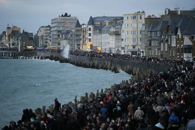 People gather on the waterfront to watch the incoming high tide in Saint Malo, western France, March 21, 2015. (Photo by Stephane Mahe/Reuters)