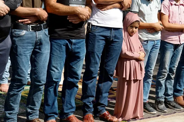 A girl stands among men while they pray as Palestinians take part in a protest following Israeli strikes on Gaza, in Nablus, in the Israeli-occupied West Bank on October 13, 2023. (Photo by Raneen Sawafta/Reuters)