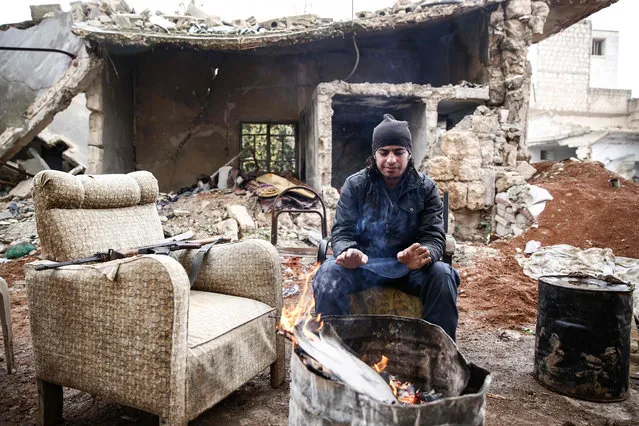 A Turkey backed Syrian rebel- fighter warms himself by a fire at a position near the city of al- Bab in Aleppo province on the border with Turkey, on November 26, 2018. (Photo by Nazeer Al-Khatib/AFP Photo)