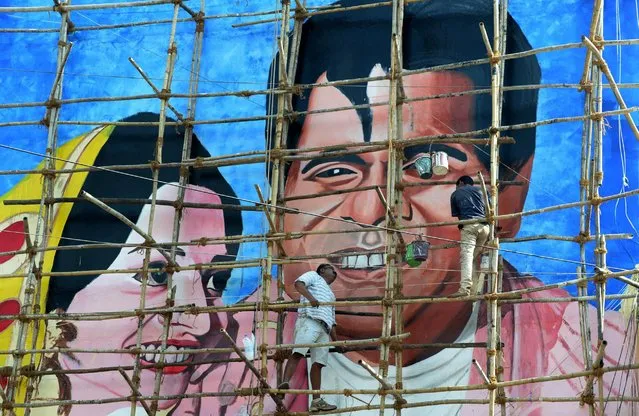 Indian artist Ranjit Dahiya (L) instructs a worker as they work on a wall mural of Bollywood actor Dilip Kumar in Mumbai, December 29, 2016. Artists from the Bollywood Art Project (BAP), an urban public art project, aim to transform the walls of the city with graffiti art influenced by the 70-year old design tradition of hand painted Bollywood posters, as an ode to Indian Cinema. (Photo by Indranil Mukherjee/AFP Photo)