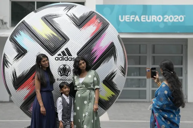 People take photographs beside a large football outside of Wembley stadium in London, Friday, July 9, 2021. The Euro 2020 soccer championship final match between Italy and England will be played at Wembley stadium on Sunday. (Photo by Frank Augstein/AP Photo)