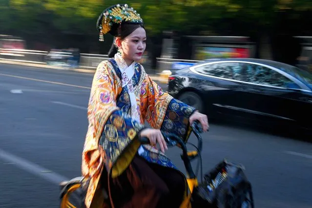 A woman dressed in Qing dynasty style clothing rides a bicycle along a street near the Forbidden City in Beijing on October 24, 2023. (Photo by Wang Zhao/AFP Photo)
