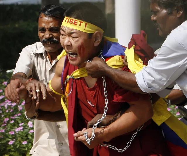 A Tibetan exile is led out by guards from inside the Chinese Embassy compound in New Delhi,October 2007. (Photo by Desmond Boylan/Reuters)