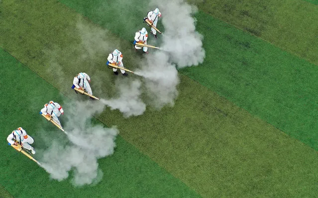 This aerial photo taken on August 23, 2021 shows staff members spraying disinfectant at a school ahead of the new semester in Bozhou in China's eastern Anhui province. (Photo by AFP Photo/China Stringer Network)