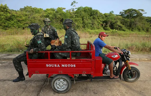 Brazilian army forces soldiers take a ride at the border of Brazil with Colombia during a training which aims to increase the security along borders, in Vila Bittencourt, Amazon State, Brazil, January 18, 2017. (Photo by Adriano Machado/Reuters)