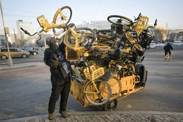A worker collects rental bicycles along a street in Beijing on December 28, 2023. (Photo by Pedro Pardo/AFP Photo)