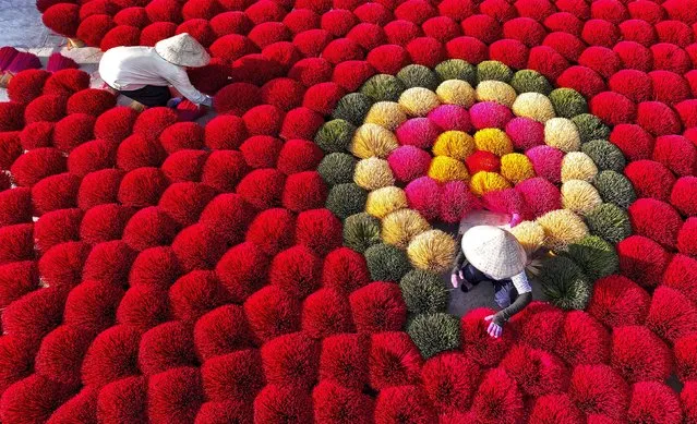 These workers are surrounded by colourful incense sticks as they arrange them to be left out to dry. The vibrant scene was snapped by Sabina Akter in Hanoi, Vietnam in the second decade of December 2023. (Photo by Sabina Akter/Solent News & Photo Agency)