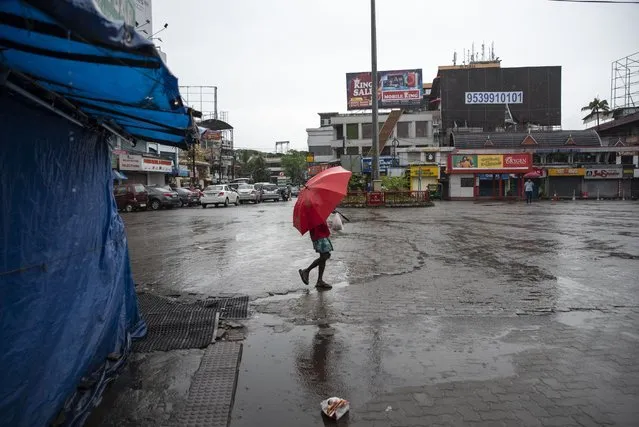 A man walks in the rain as vehicles stayed off the roads during a nation-wide shutdown to protest against the contentious farm laws in Kochi, Kerala state, India, Monday, September 27, 2021. (Photo by R.S. Iyer/AP Photo)
