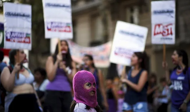 A girl wears a mask as women shout slogans during a demonstration to mark International Women's Day and to demand policies to prevent femicides outside the Congress in Buenos Aires, Argentina, March 8, 2016. (Photo by Marcos Brindicci/Reuters)