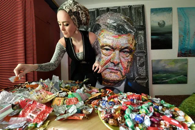 Ukrainian artist Daria Marchenko is pictured as she creates a large-scale artwork entitled “The Face of Corruption” depicting the President Petro Poroshenko made with sweet wrappers of Roshen, the Poroshenko's confectionery company, in her workshop in Kiev on March 28, 2019, ahead of the presidential elections on March 31. Daria Marchenko made headlines with a giant portrait of Russia's Vladimir Putin in bullet shells has set her sights on her own President Petro Poroshenko -- using wrappers from around 20 kilograms of sweets to craft his image. Poroshenko, who amassed a vast fortune in the chocolate business before coming to power on the back of a 2014 popular uprising, is facing an uphill re-election battle this weekend. (Photo by Sergei Supinsky/AFP Photo)