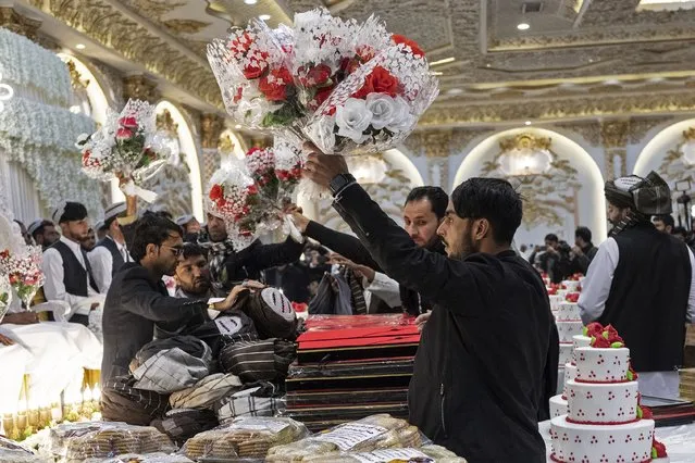 Afghan volunteers distribute flower bouquets to the grooms during a mass wedding ceremony at a wedding hall in Kabul on December 25, 2023. Fifty couples married on December 25 in a joint ceremony in the Afghan capital – a growing practice to reduce the astronomical cost of traditional weddings in the impoverished country. (Photo by Wakil Kohsar/AFP Photo)