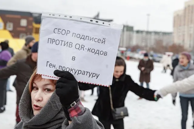 A woman holds a piece of paper that reads: “Collection of signatures against the QR codes to the Prosecutor General's Office”, as others gather during a protest in Yekaterinburg, Russia, Saturday, Novenver 13, 2021. Two bills outlining new restriction measures were introduced in parliament, with the aim of their taking effect next year. They would restrict access to many public places, as well as domestic and international trains and flights, to those who have been fully vaccinated, have recovered from COVID-19 or are medically exempt from vaccination. (Photo by Anton Basanayev/AP Photo)