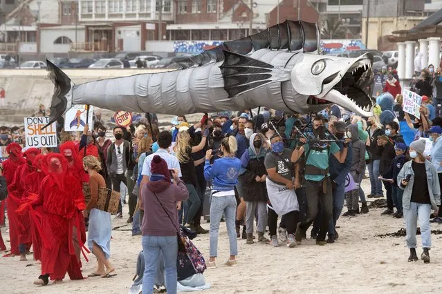 A giant puppet of a Snoek, a type of common local Mackeral, is displayed as hundreds of people take part in a protest against the plan by Dutch oil company, Shell, to conduct underwater seismic surveys along South Africa's East coast, at Muizenberg Beach, in Cape Town, on December 05, 2021. Hundreds of environmentalist demonstrators gathered on South African beaches Sunday to protest against oil and gas exploration by energy giant Shell. Activists say Shell's plans to search for oil and gas deposits off the beloved “Wild Coast” of eastern South Africa – a key tourist attraction – pose a danger to marine animals. (Photo by Rodger Bosch/AFP Photo)