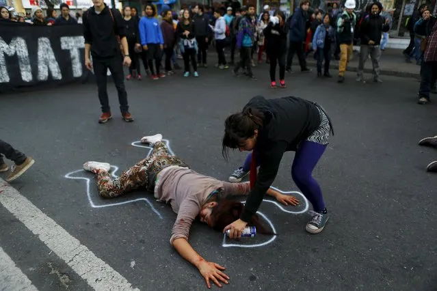 A demonstrator sprays an outline around another protester pretending to be dead, in reference to a student shot dead on May 14 after a protest march, during a rally, as Chile's President Michelle Bachelet delivers a speech inside the National Congress, in Valparaiso city, May 21, 2015. (Photo by Ivan Alvarado/Reuters)
