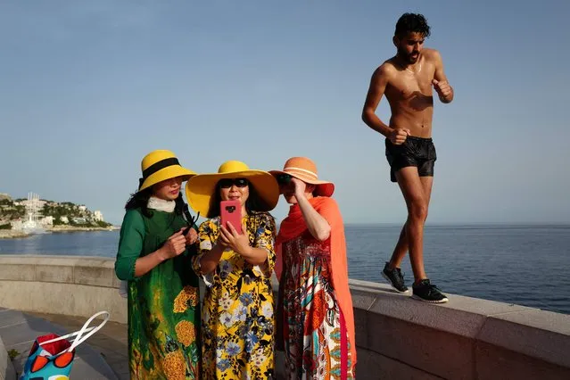 A man walks by as tourists take selfies on the French Riviera city of Nice on June 24, 2019, as temperatures soar to 33 degrees Celsius. (Photo by Valery Hache/AFP Photo)