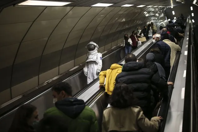A man dressed as an astronaut takes an escalators in a metro station as part of a campaign to promote a NASA Space Exhibition, in Istanbul, Turkey, Saturday, December 4, 2021. (Photo by Emrah Gurel/AP Photo)