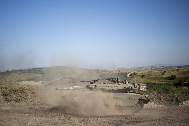 An Israeli tank moves into position in the Israeli controlled Golan Heights during fighting between forces loyal to Syrian President Bashar Assad and rebels in the Druze village of Khader in Syria, Tuesday, June 16, 2015. As many as 20 members of the Druze minority sect were killed last week, the deadliest violence against the Druze since Syria's conflict started in March 2011, sparking fears of a massacre against the sect. (AP Photo/Ariel Schalit)