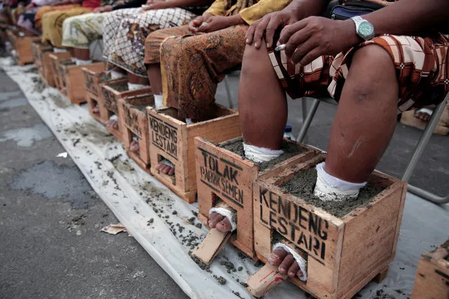 Villagers whose feet are cast in cement blocks sit on a chair as part of four days of protest to draw attention to what they say is environmental damage to their farmland from a cement factory, in Rembang, Central Java, outside the presidential palace in Jakarta, Indonesia March 16, 2017. (Photo by Reuters/Beawiharta)