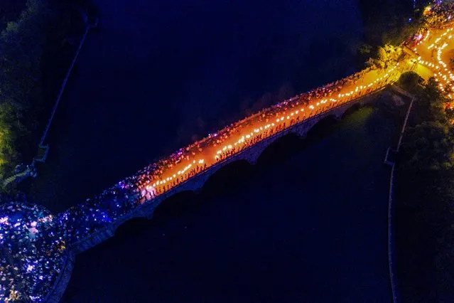 This aerial photo taken on July 29, 2019 shows people walking on a bridge with torches as they celebrate the torch festival in Bijie, China's southwestern Guizhou province. (Photo by AFP Photo/China Stringer Network)