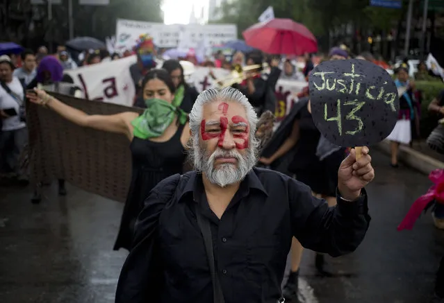 A demonstrator with the number 43 painted on his face and a sign with the word “Justice” written in Spanish in reference to the 43 missing students from a rural teachers college, marches in protest, marking 30 months since their disappearance, in Mexico City, Sunday, March 26, 2017. The federal prosecutor claimed that the students were detained by local police and handed over to a drug gang, who killed them and burned their bodies, but a group of experts from the Inter-American Commission on Human Rights does not agree with that hypothesis. (Photo by Eduardo Verdugo/AP Photo)