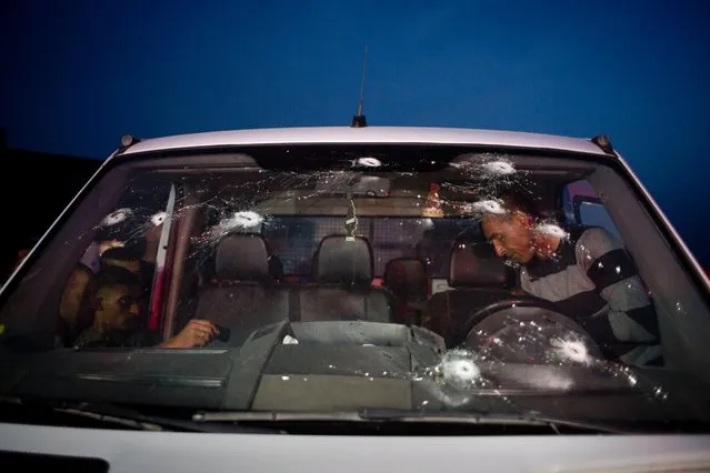 Palestinian men inspect a vehicle with a bullet shattered windshield at the site of a ramming attack against Israeli troops, in the West Bank city of Ramallah, May 3, 2016. A Palestinian rammed his vehicle into a group of Israeli soldiers in the West Bank, wounding three of them, one seriously. Soldiers at the scene opened fire and killed the attacker, the Israeli army said. (Photo by Nasser Nasser/AP Photo)