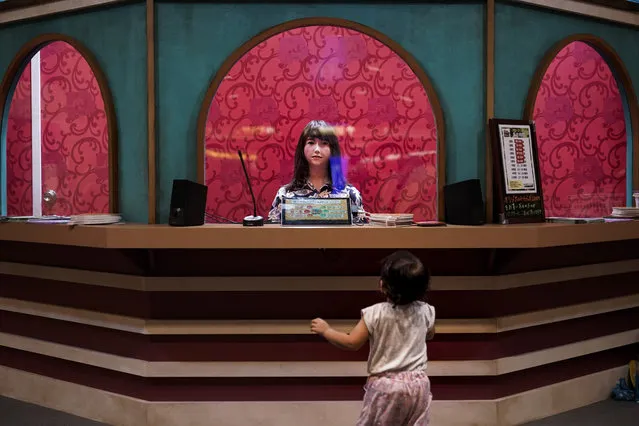 A baby girl looks at a humanoid robot sitting in a box office Friday, August 23, 2019, in Tokyo. (Photo by Jae C. Hong/AP Photo)