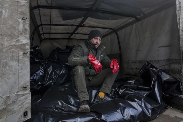 A mortuary worker sits on body bags before they were transported to be buried in a mass grave on the outskirts of Mariupol, Ukraine, Wednesday, March 9, 2022. (Photo by Evgeniy Maloletka/AP Photo)