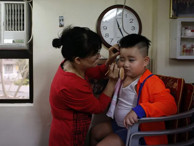 Rex Chan, 5, receives make up before taking part in a Bun Festival parade at Hong Kong's Cheung Chau island May 6, 2014. The festival celebrates the islanders' deliverance from famine many centuries ago and is meant to placate ghosts and restless spirits. (Photo by Bobby Yip/Reuters)