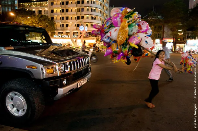 A luxury Hummer is seen parked outside an expensive restaurant as a woman carrying ballons walks past