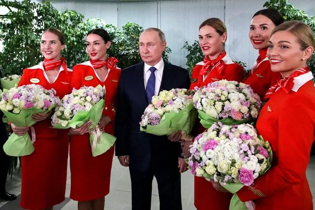 Russian President Vladimir Putin (C) poses for photo with Aeroflot employees during his visit to Aeroflot aviation training complex outside Moscow on March 5, 2022. Russian President Vladimir Putin said Saturday that any country that sought to impose a no-fly zone over Ukraine would be considered by Moscow to have entered the conflict. (Photo by Mikhail Klimentyev/Sputnik/AFP Photo) 