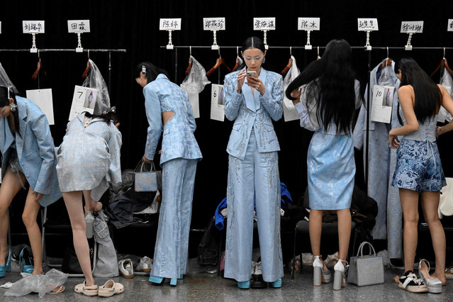 Models prepare backstage before a creation from the Saint Joy by Bian Huizhong during the China Fashion Week in Beijing on March 30, 2023. (Photo by Wang Zhao/AFP Photo)
