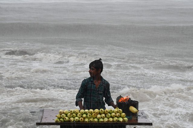 A corn seller waits for customers during rain showers near the sea front in Mumbai on July 8, 2024. Intense monsoon storms battered India on July 8, flooding parts of the financial capital Mumbai, while lightning in the eastern state of Bihar killed at least 10 people, government officials said. (Photo by Punit Paranjpe/AFP Photo)