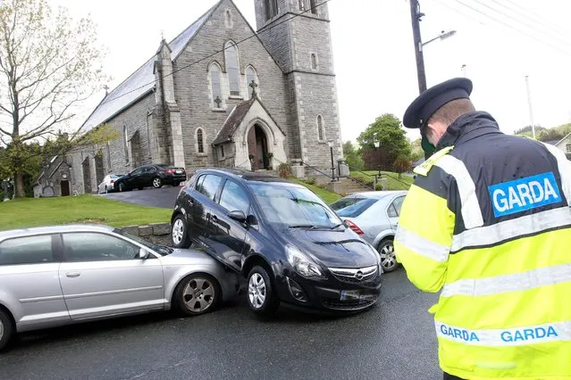 A Garda takes notes in Aughrim, Co.Wicklow after a car rolled from the chapel grounds where the oocupants were attending a wedding on Saturday afternoon, the handbrake had been left off and the high winds push the car over the wall and onto a parked Audi. (Photo by Ann Egan/PA Wire)