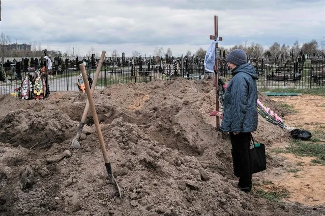 Nadia looks at the coffin of her husband who was killed, after the funeral at a cemetery in Bucha, on April 18, 2022, during the Russian invasion of Ukraine. (Photo by Yasuyoshi Chiba/AFP Photo)