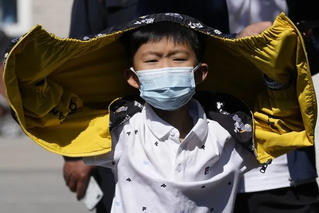 A child wearing a mask lines up for COVID test on Sunday, May 1, 2022, in Beijing. (Photo by Ng Han Guan/AP Photo)