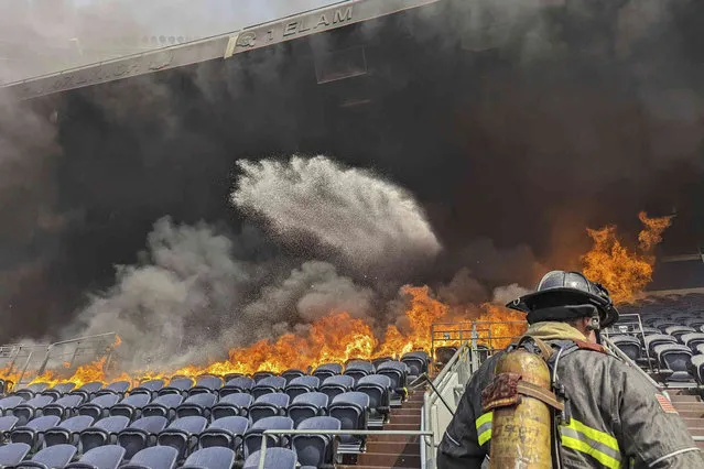 In this photo provided by the Denver Fire Department, firefighters battle flames at Empower Field at Mile High stadium in Denver, Thursday, March 24, 2022. Firefighters have extinguished a blaze that torched several rows of seats and a suite area at the Denver Broncos' stadium. The fire broke out in the third-level and burned at least six rows of seats in two sections. (Photo by Denver Fire Department via AP Photo)