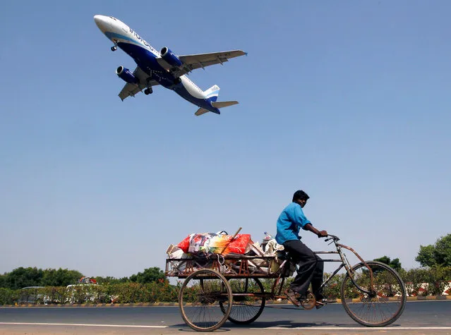 An IndiGo Airlines aircraft prepares to land as a man paddles his cycle rickshaw in Ahmedabad, India, October 26, 2015. (Photo by Amit Dave/Reuters)