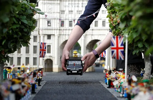 Legoland modeller Freya Groom poses for a photograph while placing a model of Britain’s Queen Elizabeth in a vehicle near a model of Admiralty Arch in The Mall, at Legoland in Windsor, Britain, May 31, 2022. (Photo by Peter Nicholls/Reuters)